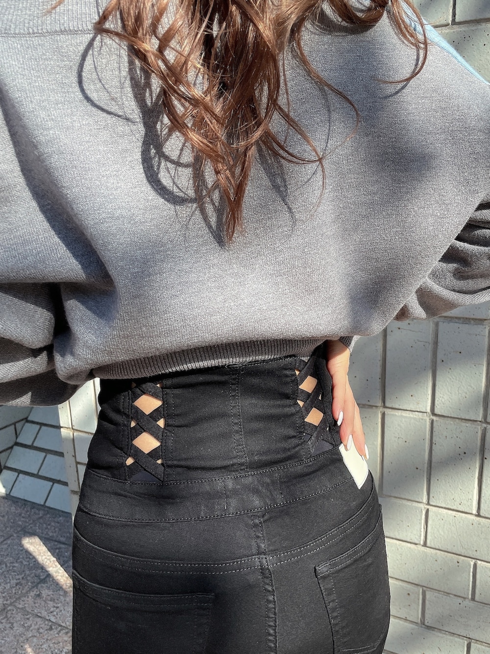 グレー系のニット/セーター、ブラック系のキャミソール、ブラック系のデニムパンツを着用したレディースの冬コーディネートの6枚目の写真