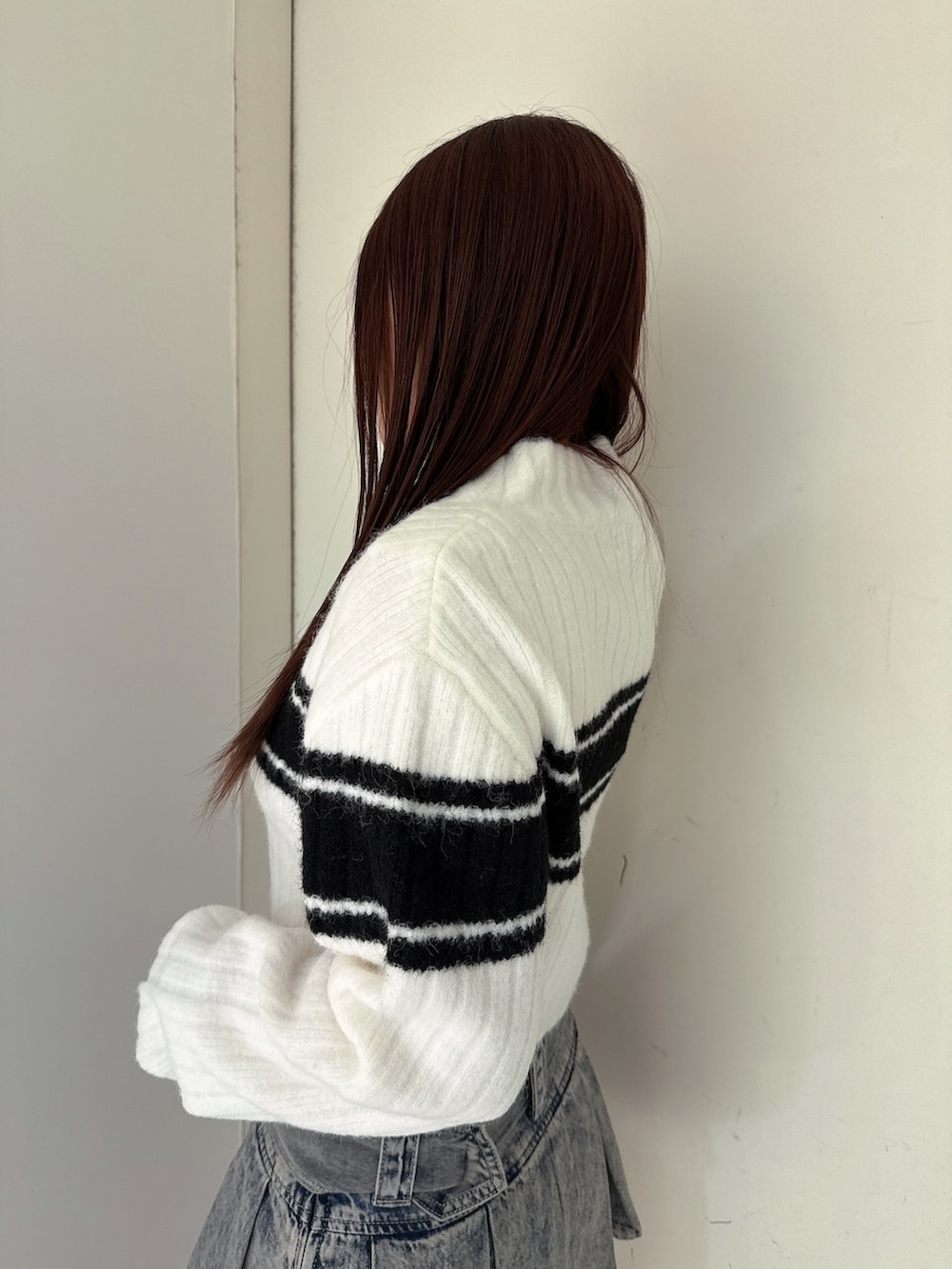 ブルー系のデニムスカート、ブラック系のブーツ、ホワイト系のニット/セーターを着用したレディースの冬コーディネートの5枚目の写真