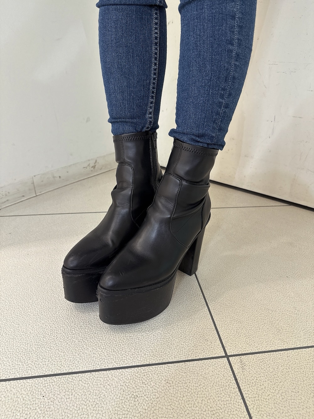 ブラック系のニット/セーター、ブラック系のデニムパンツ、ブラック系のブーツを着用したレディースの秋コーディネートの10枚目の写真