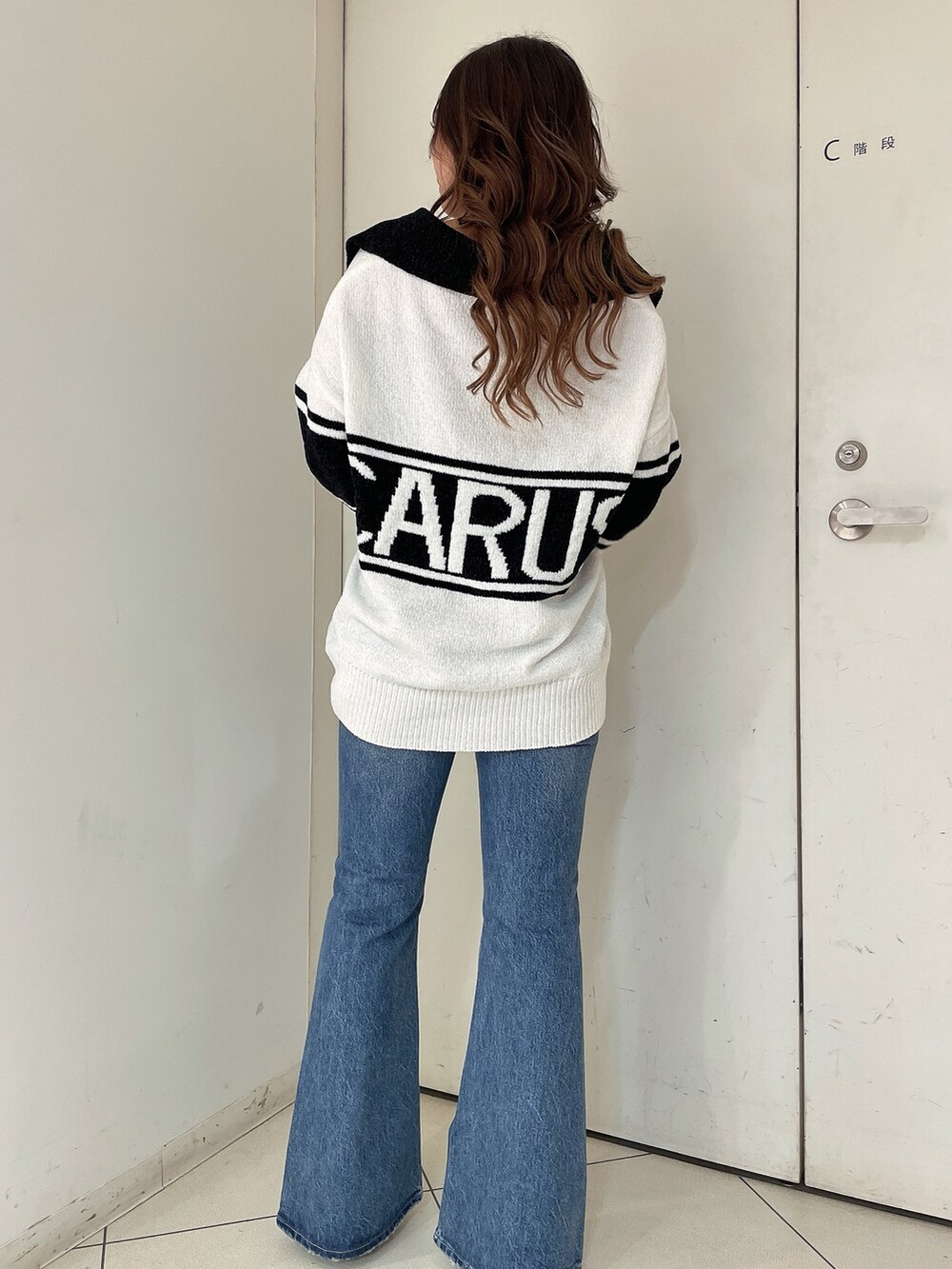 ホワイト系のニット/セーター、ブルー系のデニムパンツ、ホワイト系のパンプスを着用したレディースの秋コーディネートの3枚目の写真