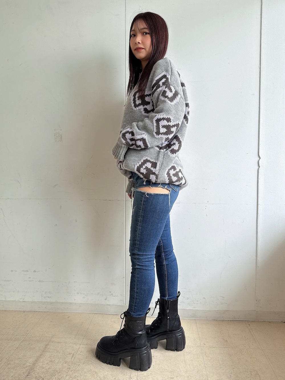 グレー系のニット/セーター、ブルー系のデニムパンツ、ブラック系のブーツを着用したレディースの秋コーディネートの2枚目の写真