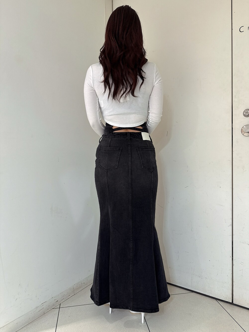 ブラック系のデニムスカート、ブラック系のTシャツ/カットソー、ホワイト系のパンプスを着用したレディースの秋コーディネートの3枚目の写真