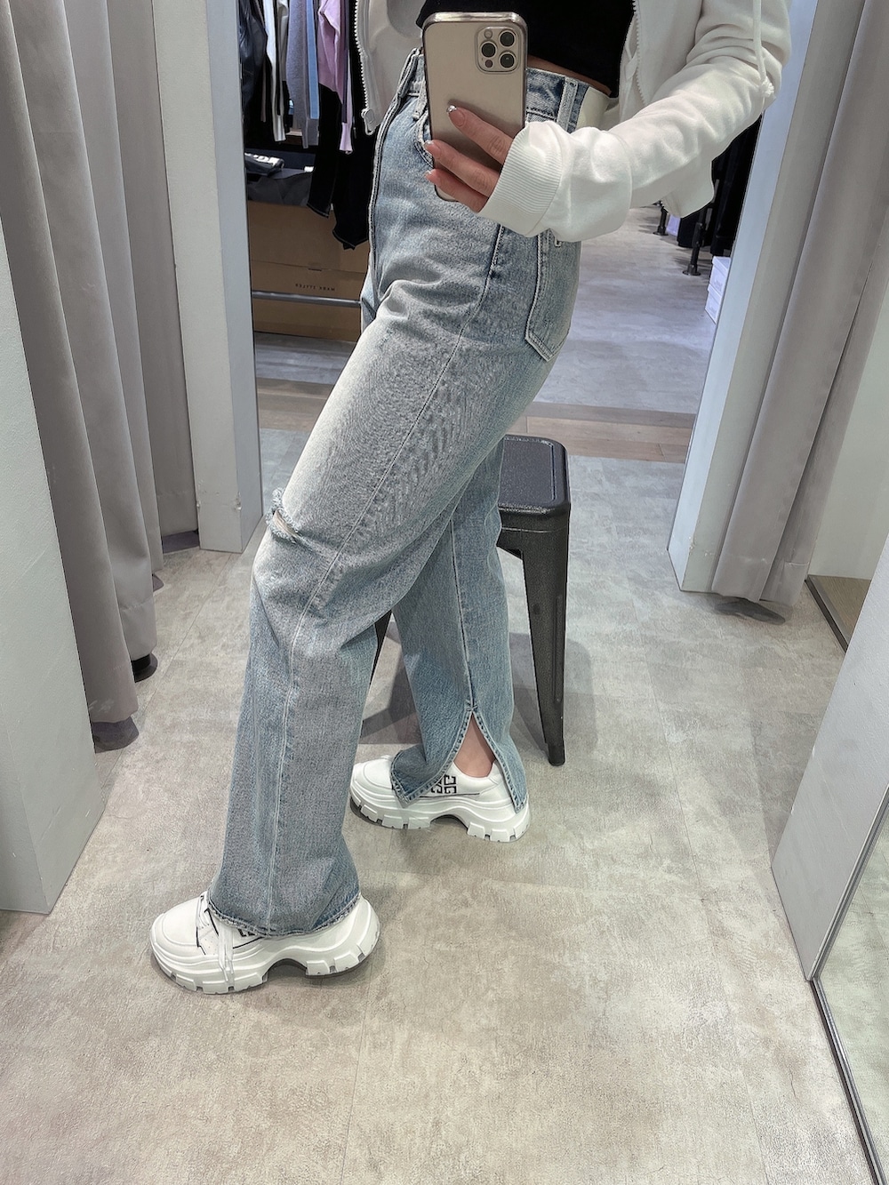 ホワイト系のパーカー、ブラック系のチューブトップ、ブルー系のデニムパンツを着用したレディースの冬コーディネートの5枚目の写真