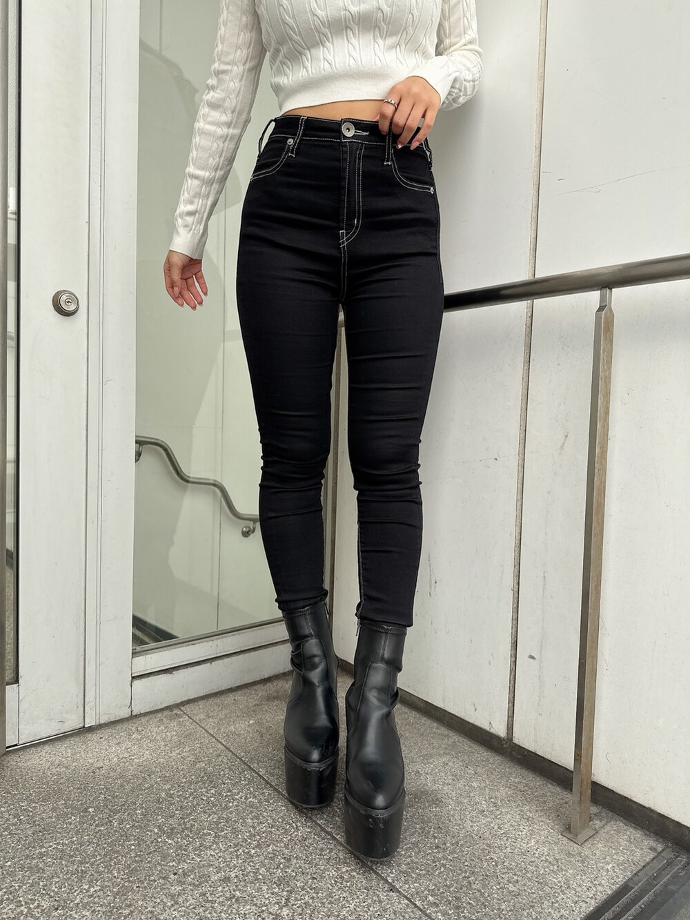 ブラック系のデニムパンツ、ブラック系のブーツ、ホワイト系のその他アウターを着用したレディースの冬コーディネートの7枚目の写真