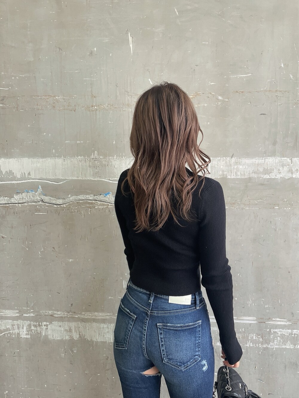 ブラック系のニット/セーター、ブラック系のチェスターコート、ブルー系のデニムパンツを着用したレディースの冬コーディネートの5枚目の写真