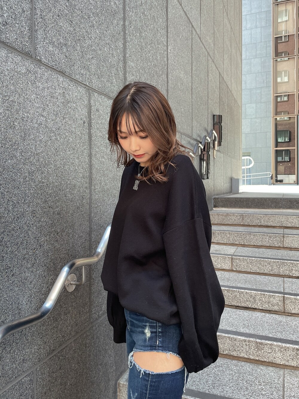 ブラック系のニット/セーター、ブルー系のデニムパンツ、ブラック系のパンプスを着用したレディースの冬コーディネートの4枚目の写真