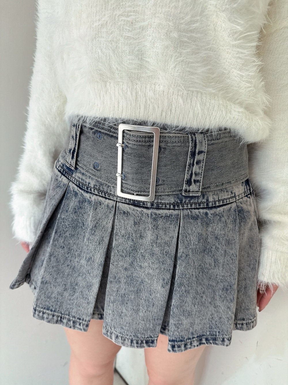 ブルー系のデニムスカート、ブラック系のブーツ、ホワイト系のニット/セーターを着用したレディースの冬コーディネートの8枚目の写真