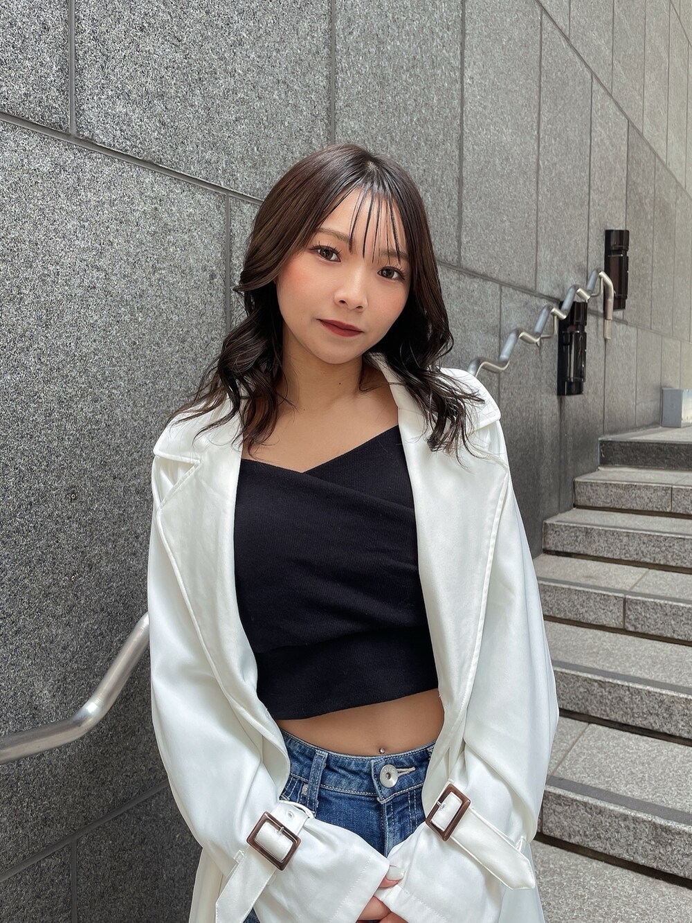 ホワイト系のトレンチコート、ブラック系のTシャツ/カットソー、ブルー系のデニムパンツを着用したレディースの春コーディネートの4枚目の写真