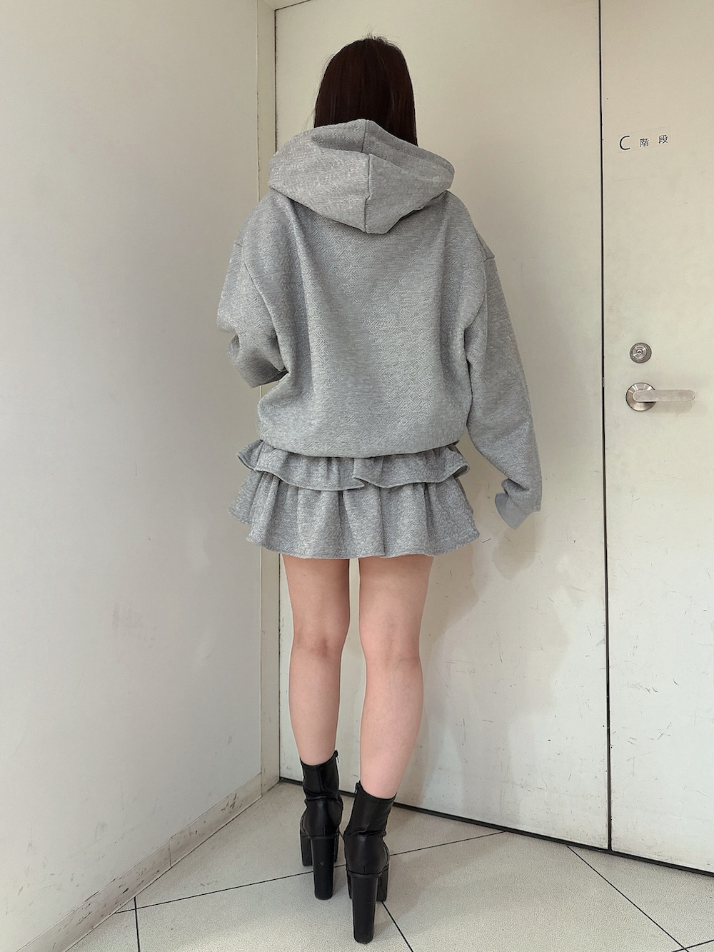 グレー系のスカート、グレー系のパーカー、ブラック系のブーツを着用したレディースの冬コーディネートの3枚目の写真