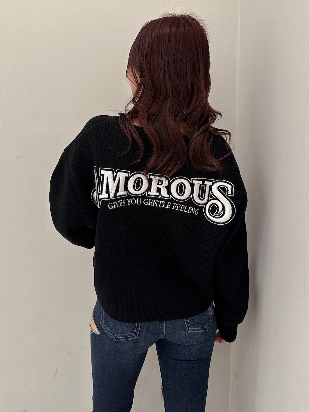 ブラック系のニット/セーター、ブルー系のデニムパンツ、ブラック系のブーツを着用したレディースの秋コーディネートの6枚目の写真