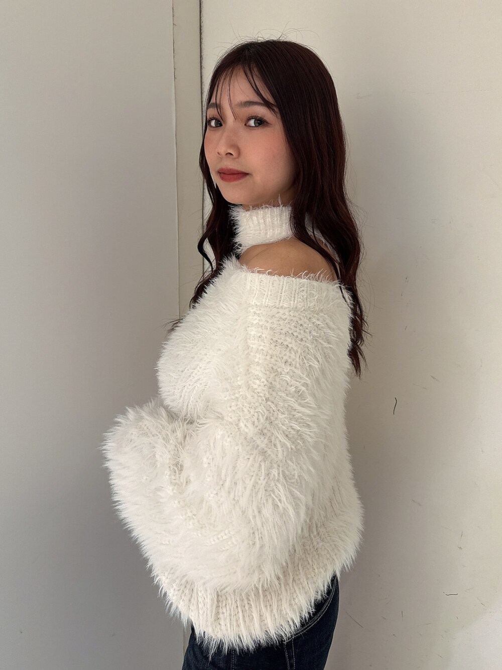ホワイト系のニット/セーター、ブルー系のデニムパンツ、ホワイト系のパンプスを着用したレディースの秋コーディネートの5枚目の写真