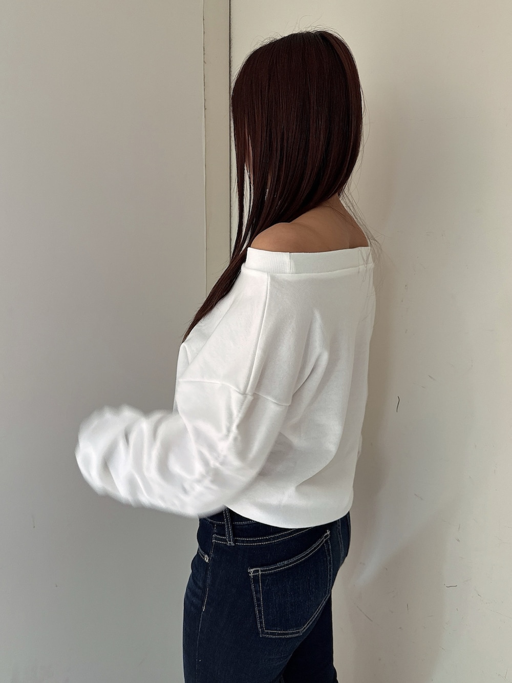 ブルー系のデニムパンツ、ブラック系のブーツ、ホワイト系のスウェットを着用したレディースの秋コーディネートの5枚目の写真