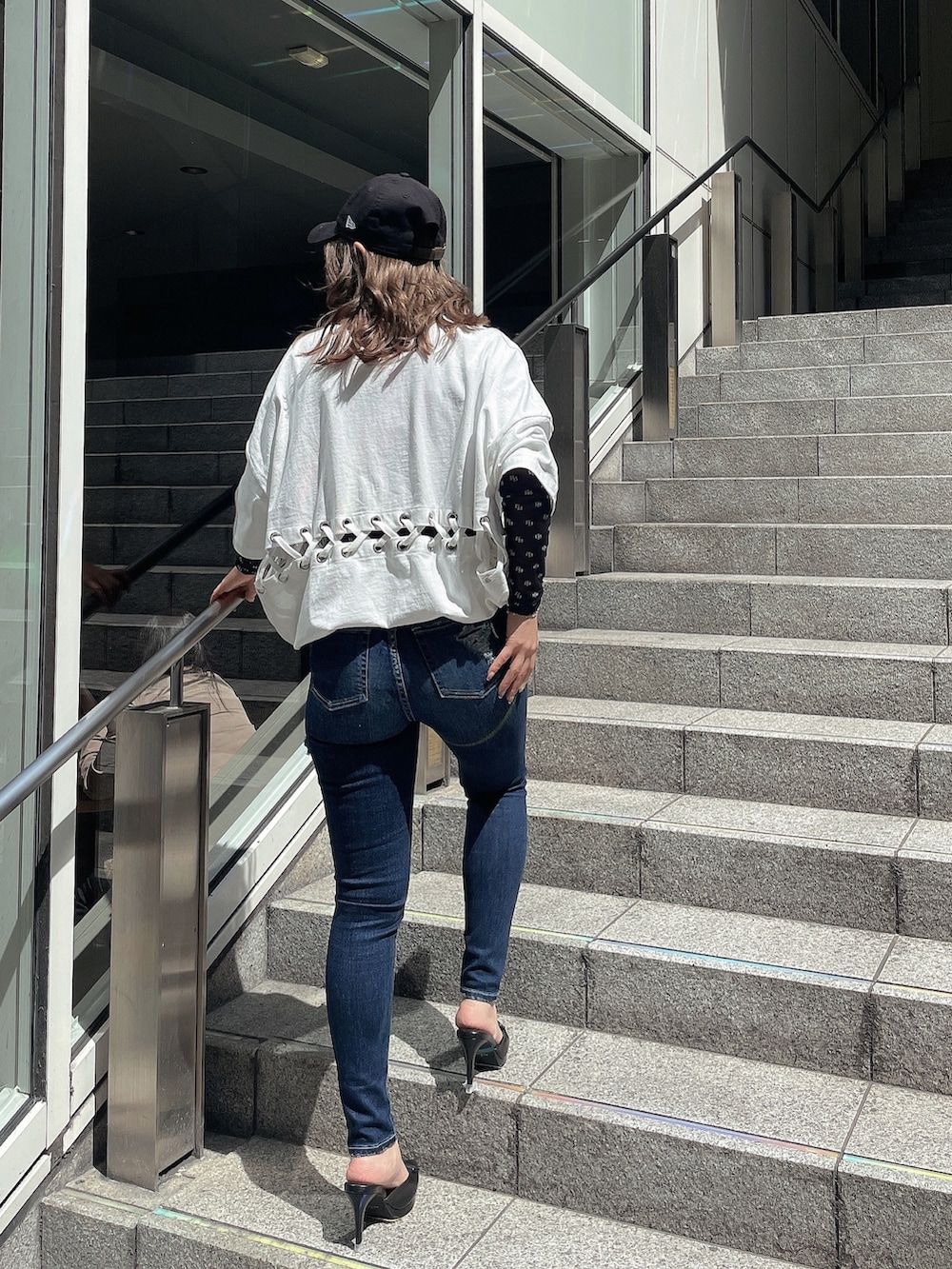 ブルー系のデニムパンツ、ブラック系のパンプス、ブラック系のTシャツ/カットソーを着用したレディースの春コーディネートの2枚目の写真