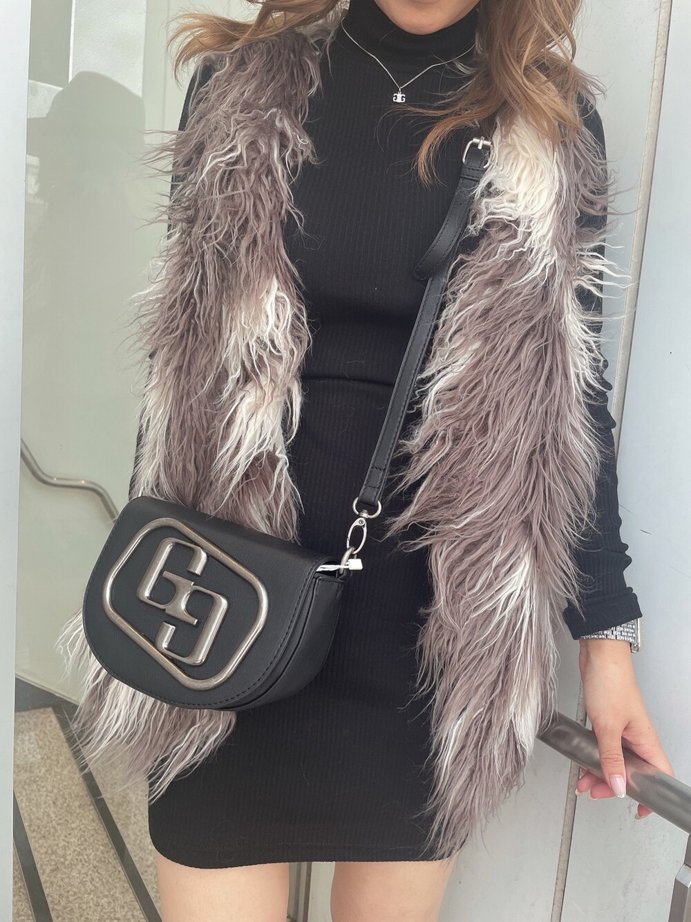 ブラック系のワンピース、その他のベスト、ブラック系のハンドバッグを着用したレディースの秋コーディネートの6枚目の写真