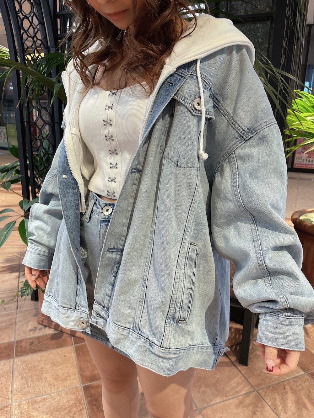 ホワイト系のキャミソール、ホワイト系のパーカー、ブルー系のデニムジャケットを着用したレディースの春コーディネートの5枚目の写真