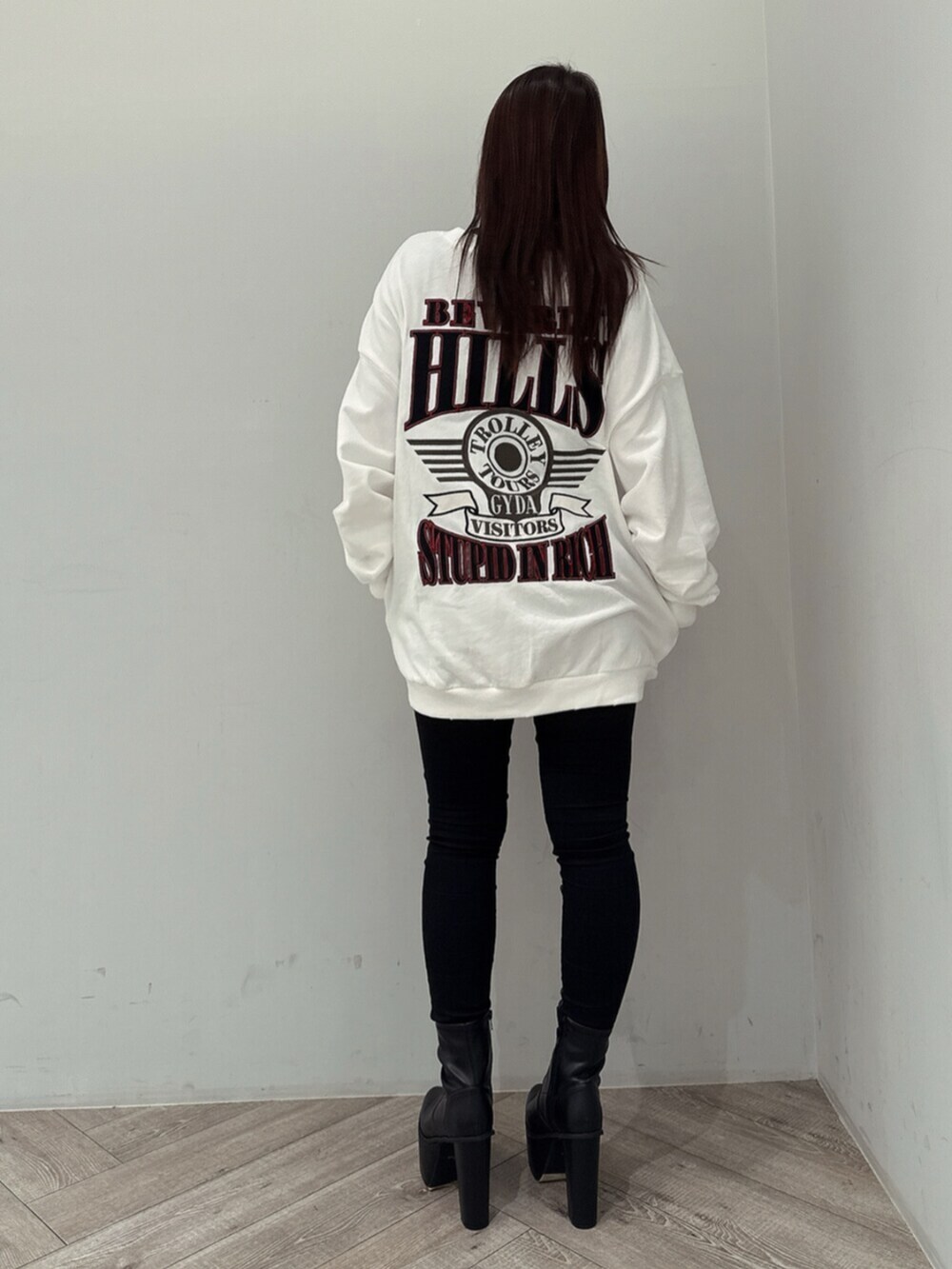 ブラック系のデニムパンツ、ホワイト系のスウェット、ブラック系のブーツを着用したレディースの夏コーディネートの3枚目の写真