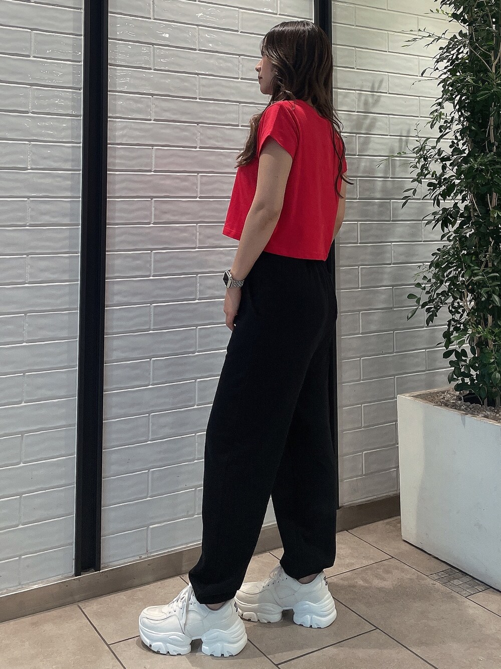 レッド系のTシャツ/カットソー、ブラック系のスウェットパンツ、ホワイト系のスニーカーを着用したレディースの夏コーディネートの2枚目の写真