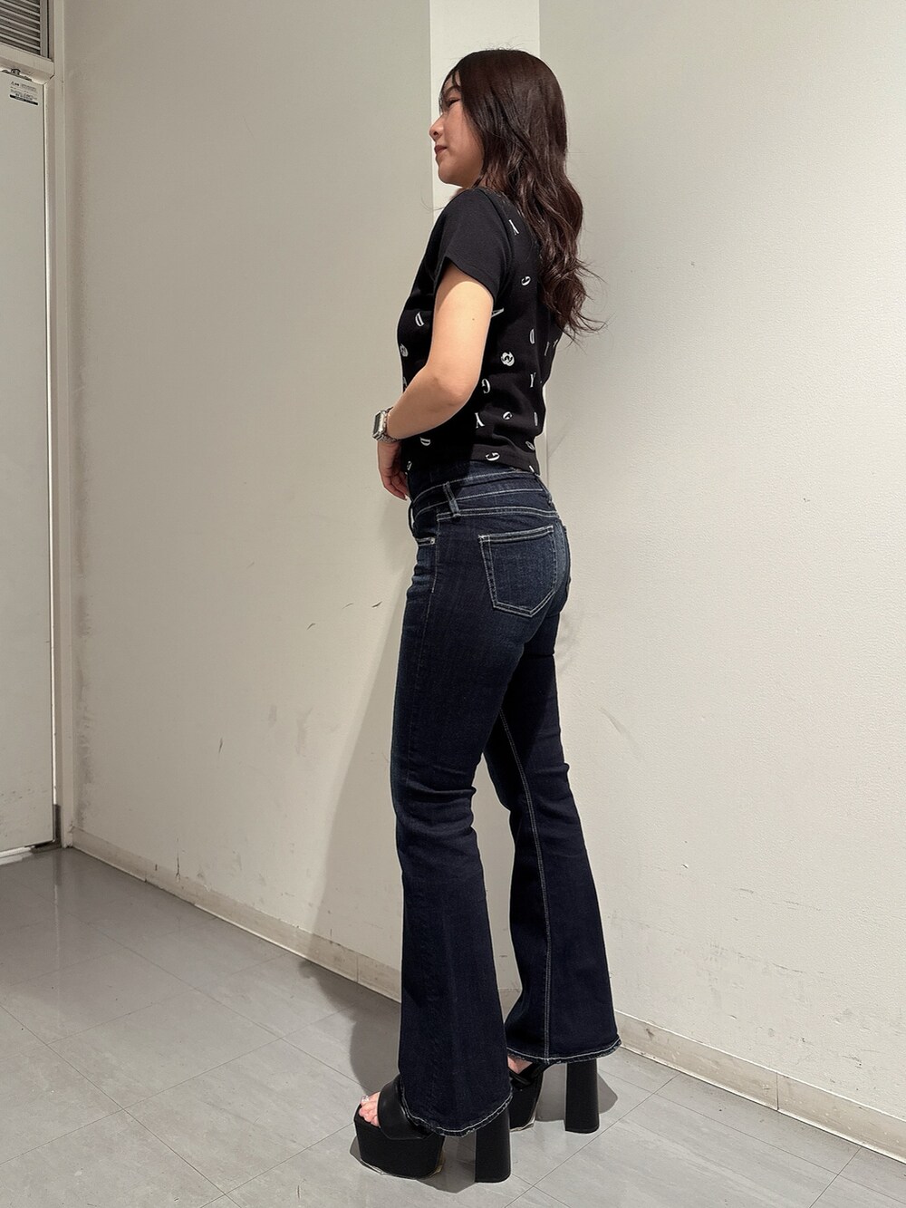 ブラック系のTシャツ/カットソー、ブルー系のデニムパンツ、ブラック系のサンダルを着用したレディースの春コーディネートの2枚目の写真