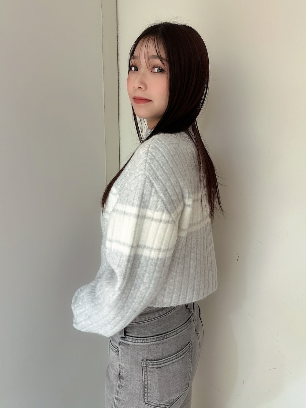 グレー系のデニムパンツ、ブラック系のブーツ、グレー系のニット/セーターを着用したレディースの冬コーディネートの5枚目の写真