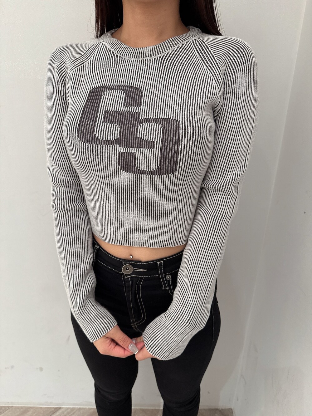 ブラック系のニット/セーター、ブラック系のデニムパンツ、ブラック系のブーツを着用したレディースの夏コーディネートの7枚目の写真