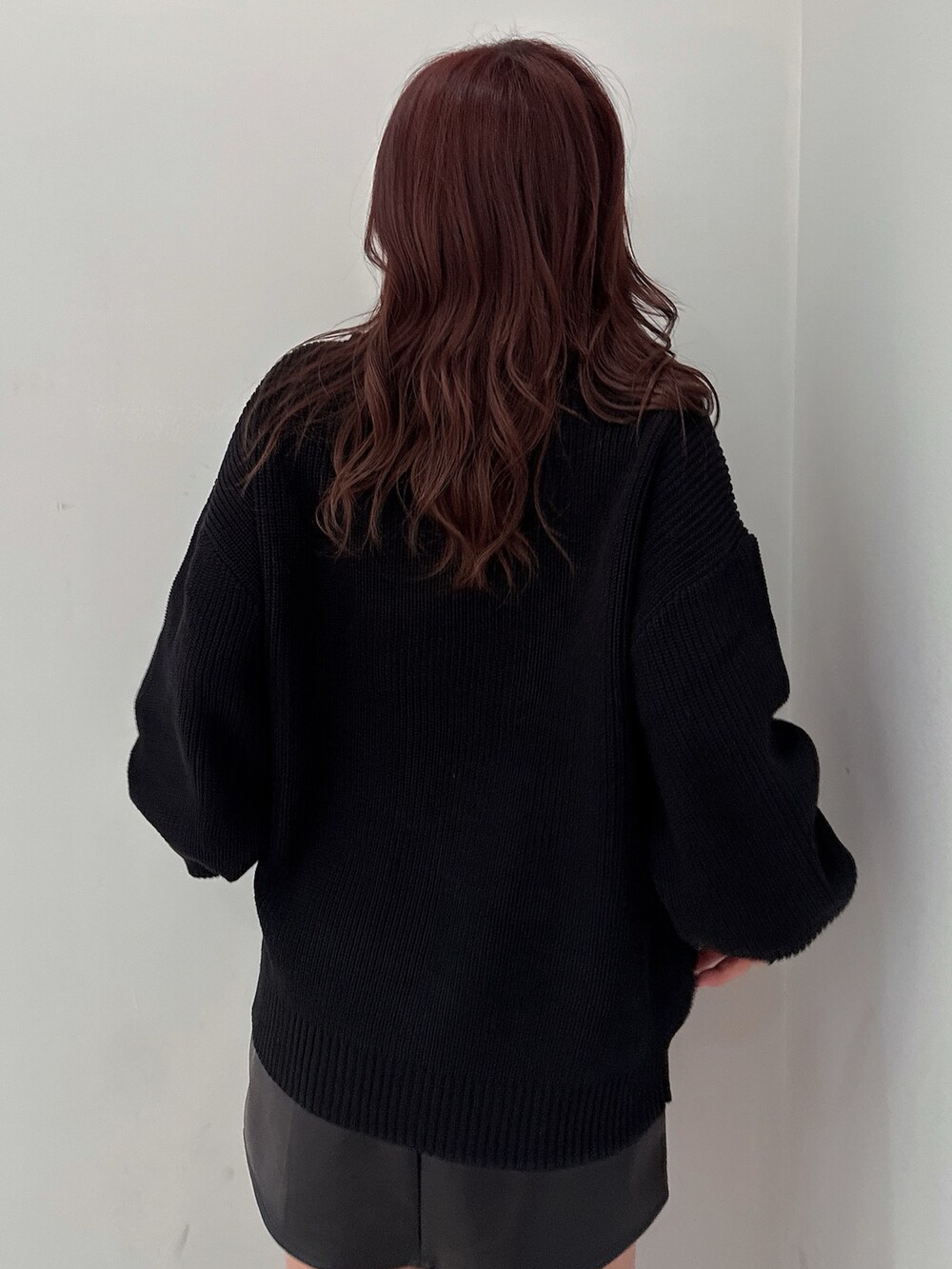 ブラック系のスカート、ブラック系のニット/セーター、ブラック系のブーツを着用したレディースの冬コーディネートの6枚目の写真