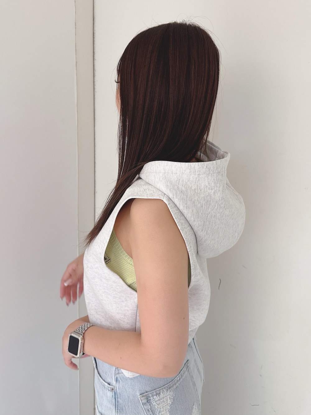 グレー系のパーカー、ブルー系のデニムパンツ、ホワイト系のサンダルを着用したレディースの夏コーディネートの5枚目の写真