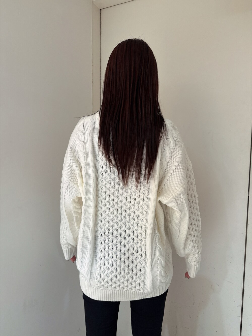 ホワイト系のニット/セーター、ブラック系のデニムパンツ、ブラック系のブーツを着用したレディースの秋コーディネートの6枚目の写真