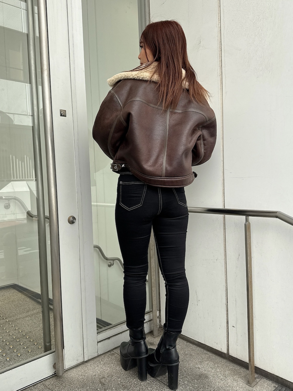 ブラック系のデニムパンツ、ブラック系のブーツ、ホワイト系のニット/セーターを着用したレディースの秋コーディネートの3枚目の写真