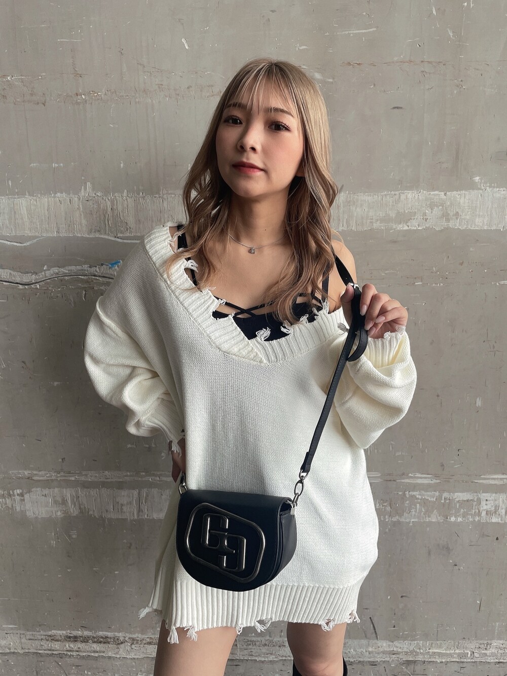 ブラック系のハンドバッグ、ホワイト系のニット/セーター、ブラック系のブーツを着用したレディースの秋コーディネートの3枚目の写真