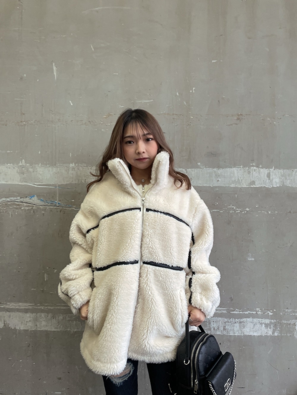 ホワイト系のブルゾン、ホワイト系のニット/セーター、ブルー系のデニムパンツを着用したレディースの冬コーディネートの4枚目の写真