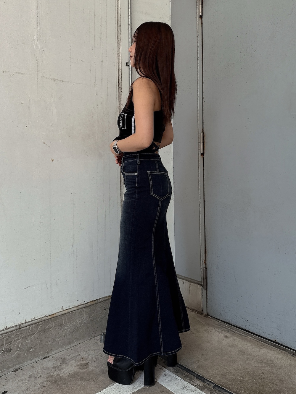 ブラック系のキャミソール、ブルー系のデニムスカート、ブラック系のサンダルを着用したレディースの夏コーディネートの2枚目の写真