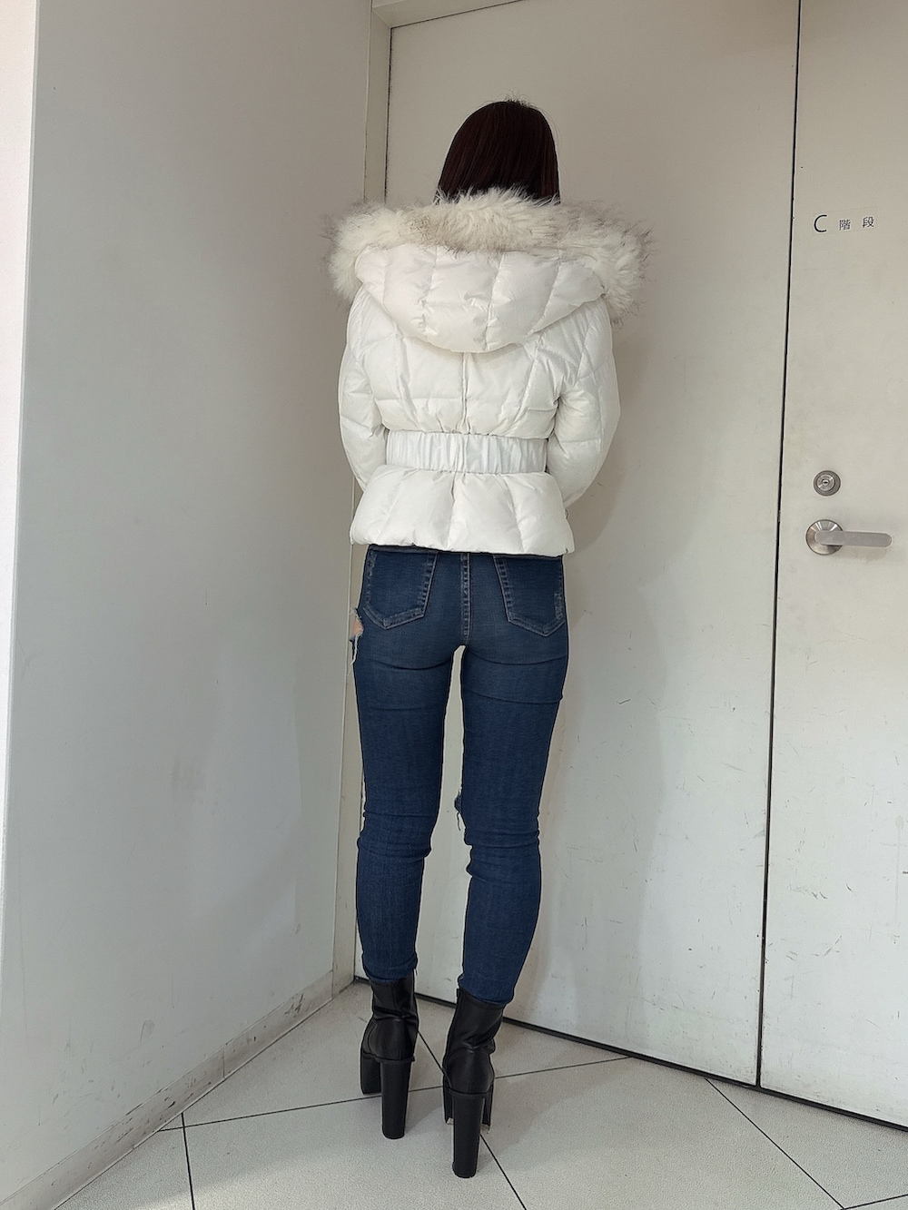 ホワイト系のダウンジャケット/コート、ブルー系のデニムパンツ、ブラック系のブーツを着用したレディースの秋コーディネートの3枚目の写真