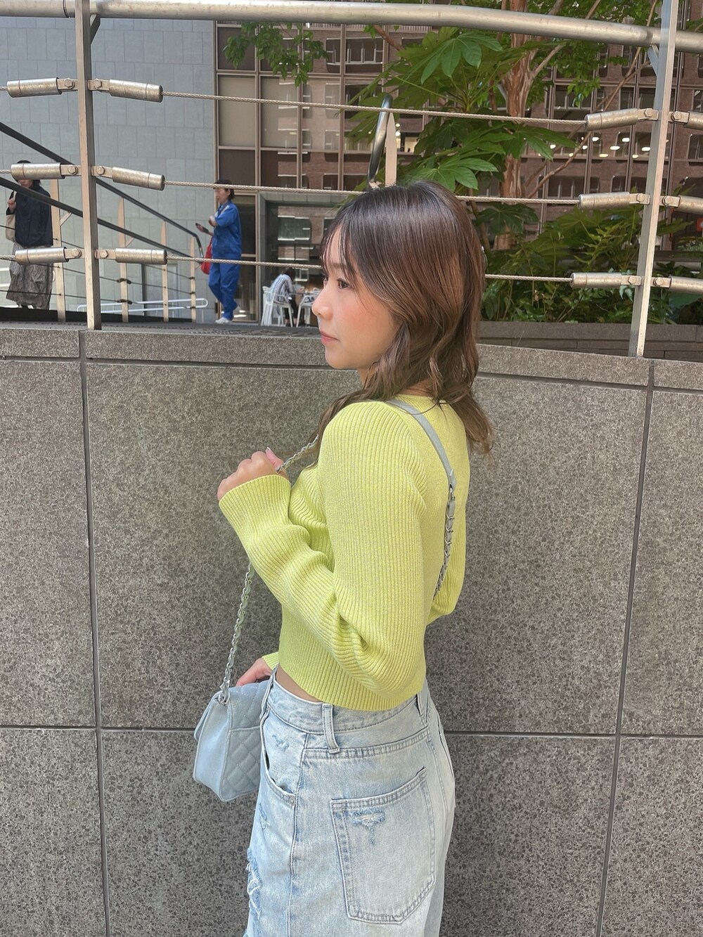 ブルー系のデニムパンツ、ホワイト系のサンダルを着用したレディースの春コーディネートの5枚目の写真