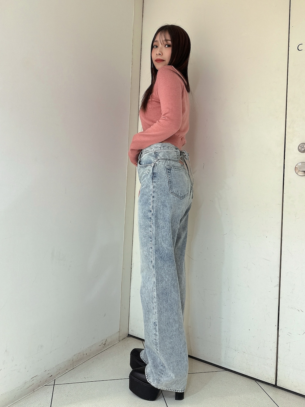 ブルー系のデニムパンツ、ピンク系のニット/セーター、ブラック系のブーツを着用したレディースの冬コーディネートの2枚目の写真