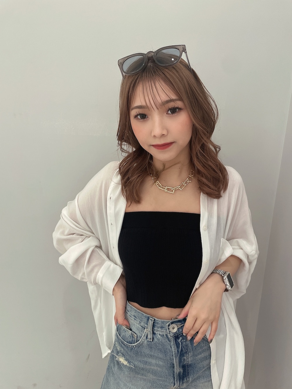 ブラック系のニット/セーター、ブルー系のデニムパンツ、ホワイト系のシャツ/ブラウスを着用したレディースの春コーディネートの4枚目の写真