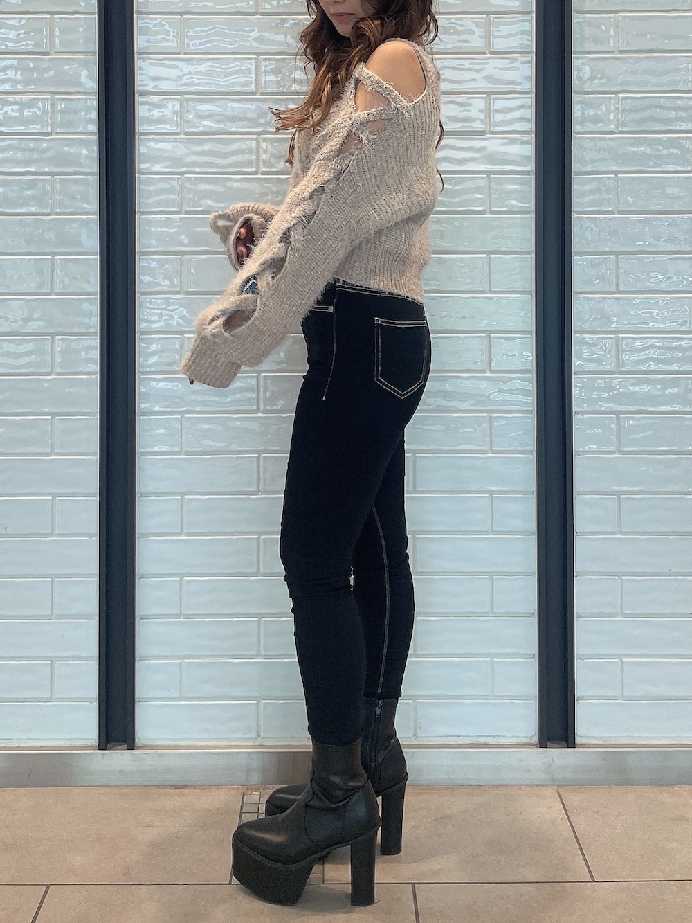 ベージュ系のニット/セーター、ブラック系のデニムパンツ、ブラック系のブーツを着用したレディースの秋コーディネートの2枚目の写真