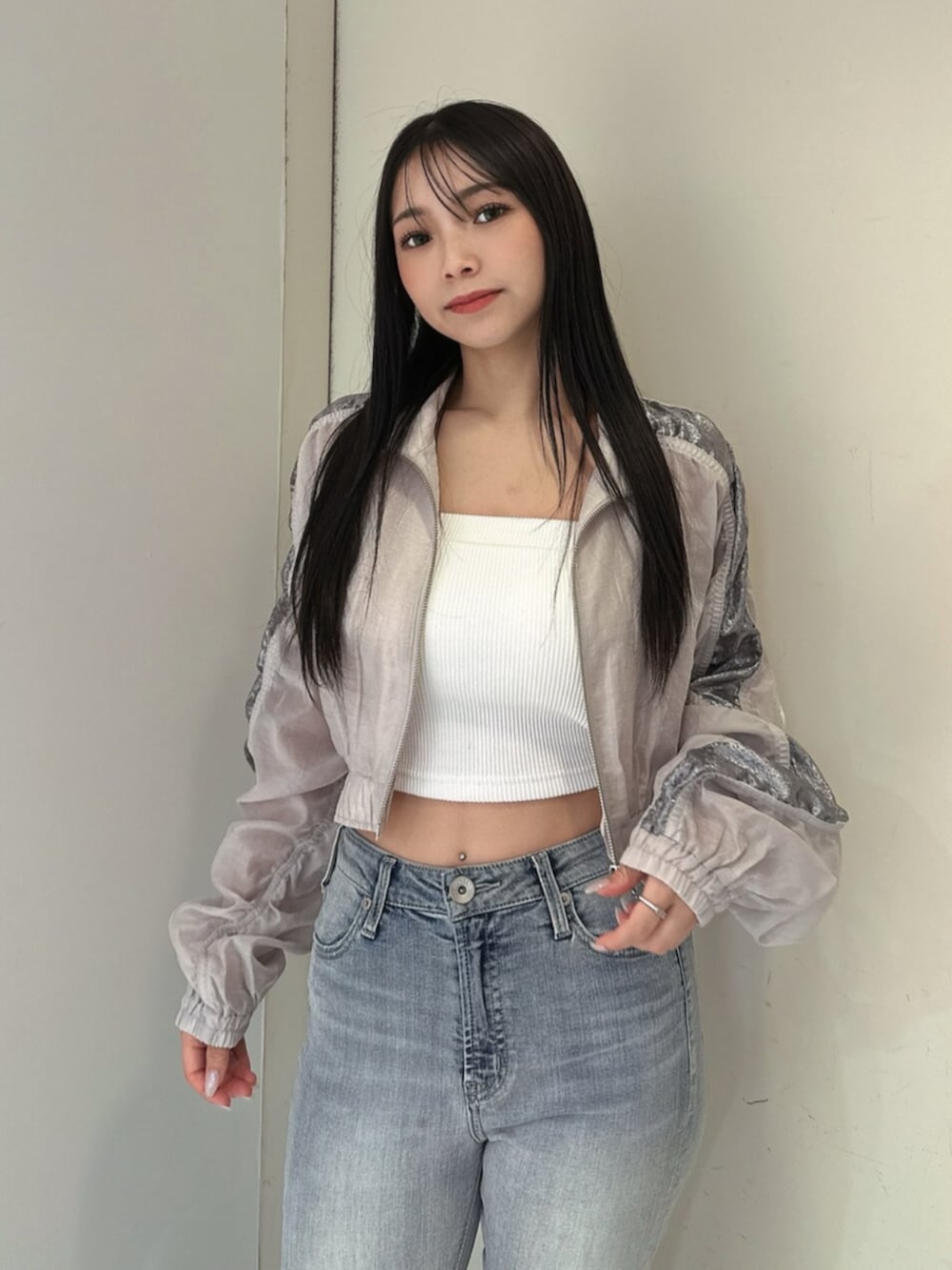 ブルー系のデニムパンツ、ブラック系のサンダル、ホワイト系のブルゾンを着用したレディースの春コーディネートの4枚目の写真