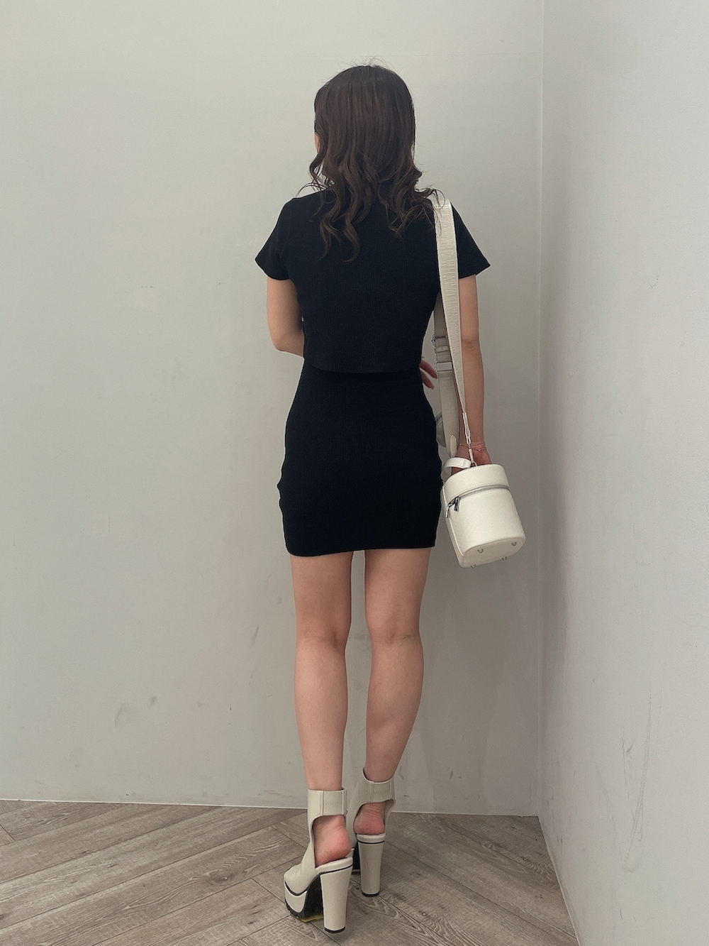 ブラック系のワンピース、ブラック系のハンドバッグ、ホワイト系のブーツを着用したレディースの春コーディネートの3枚目の写真