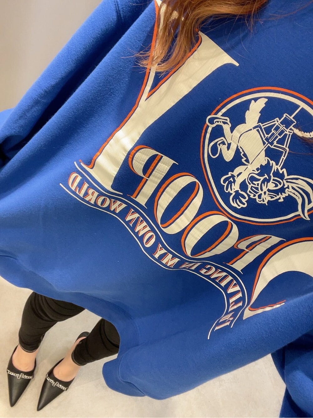 ブラック系のパンプス、ブラック系のデニムパンツ、ブルー系のスウェットを着用したレディースの秋コーディネートの4枚目の写真