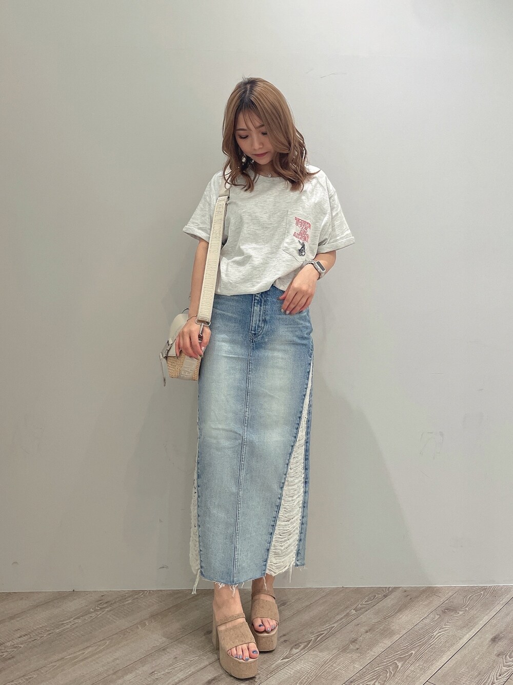 ホワイト系のTシャツ/カットソー、ブルー系のデニムスカート、ホワイト系のサンダルを着用したレディースの春コーディネートの2枚目の写真