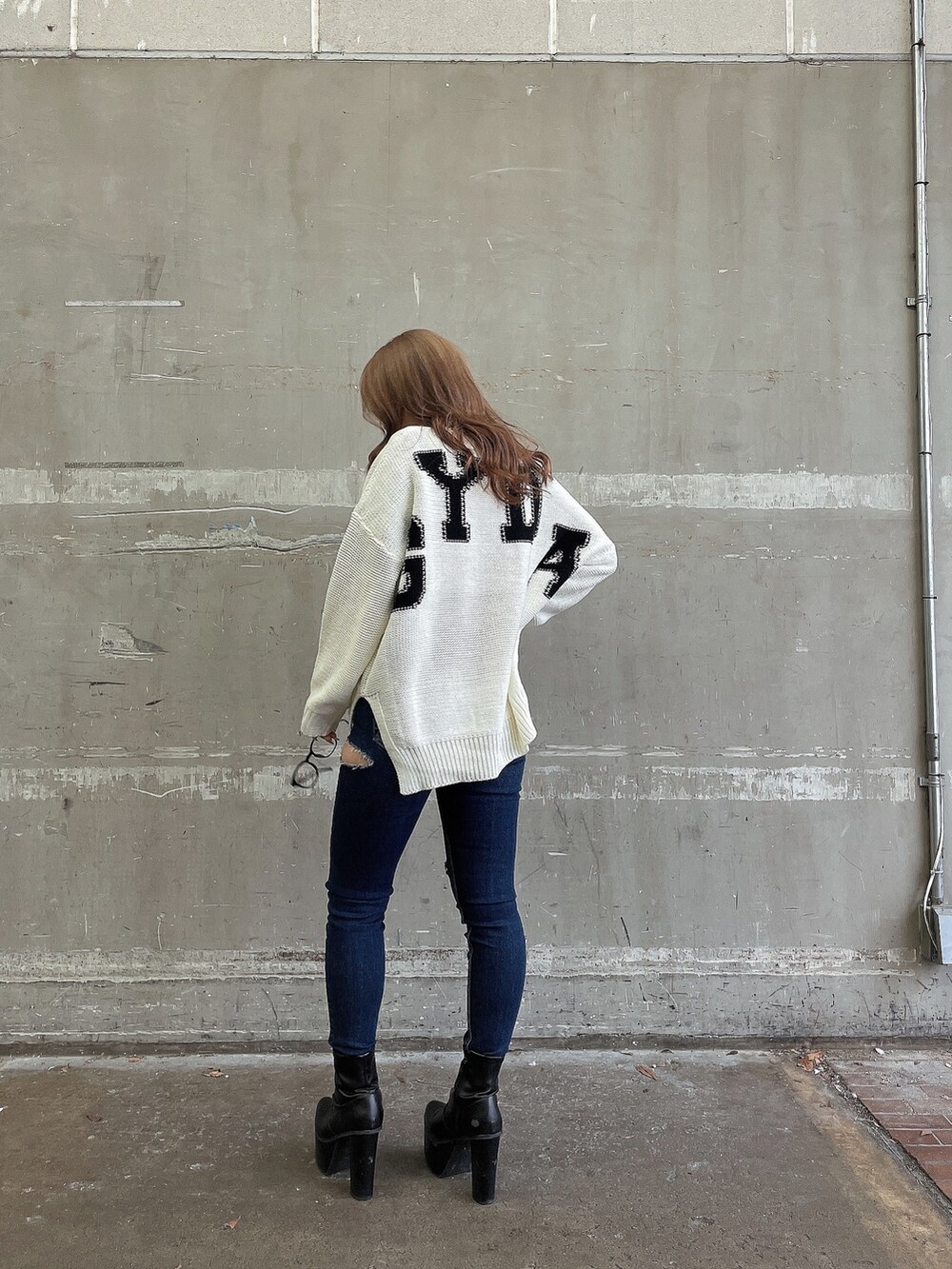 ホワイト系のニット/セーター、ブルー系のデニムパンツ、ブラック系のブーツを着用したレディースの冬コーディネートの4枚目の写真