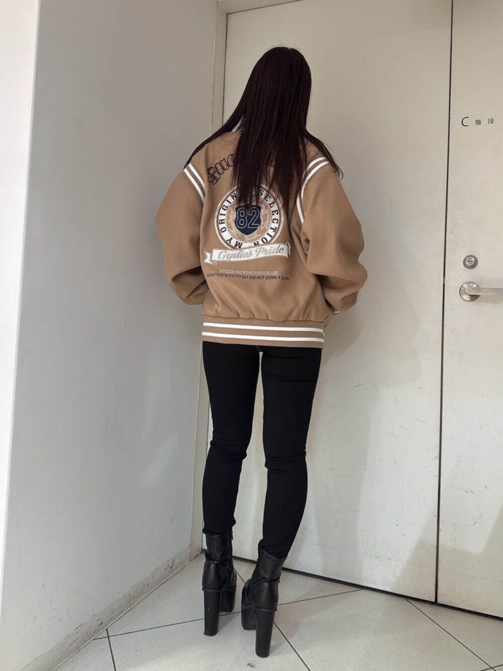 ブラック系のデニムパンツ、ブラック系のニット/セーター、ベージュ系のスタジャンを着用したレディースの秋コーディネートの3枚目の写真