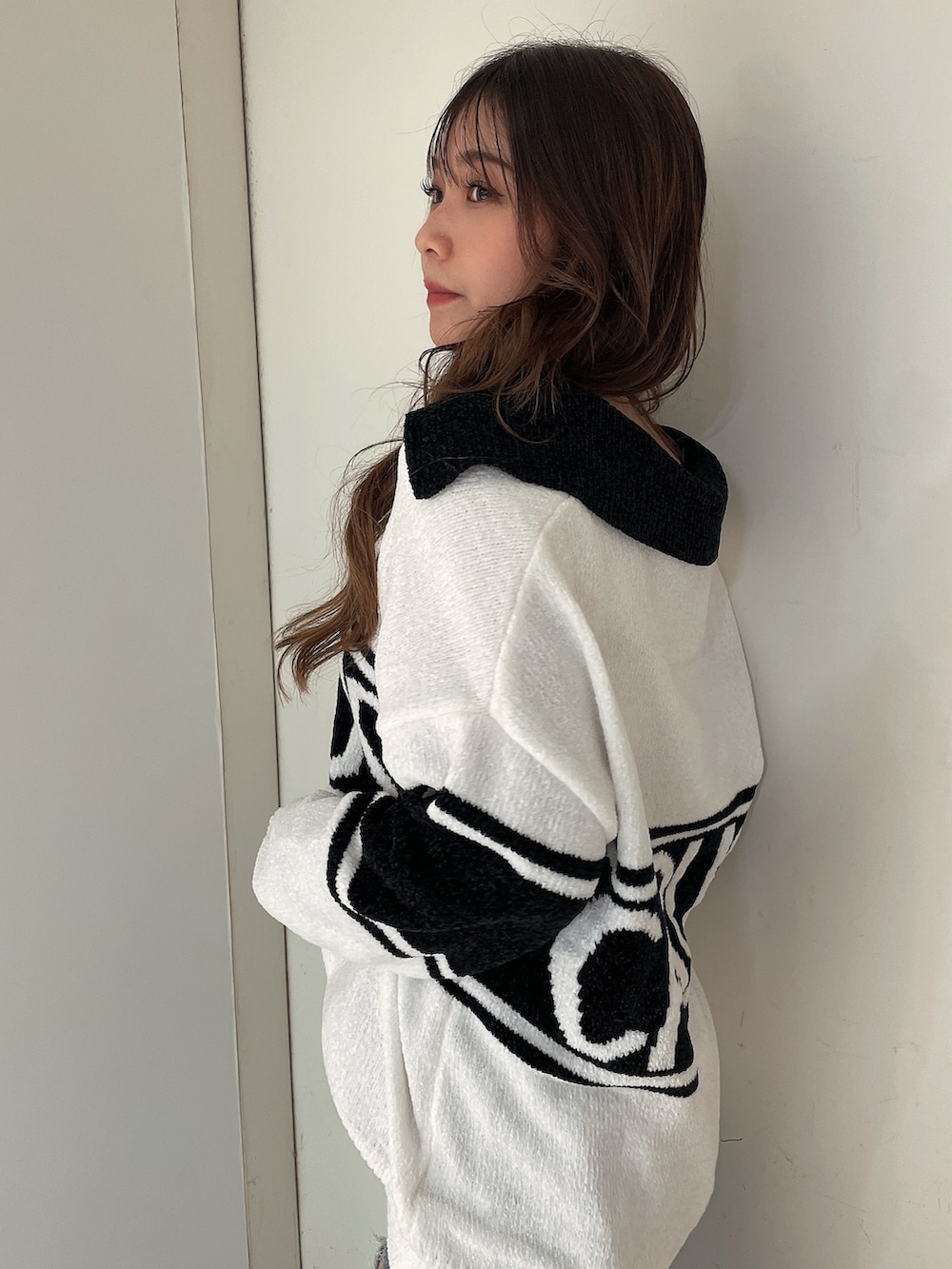 ホワイト系のニット/セーター、ブルー系のデニムパンツ、ホワイト系のパンプスを着用したレディースの秋コーディネートの5枚目の写真