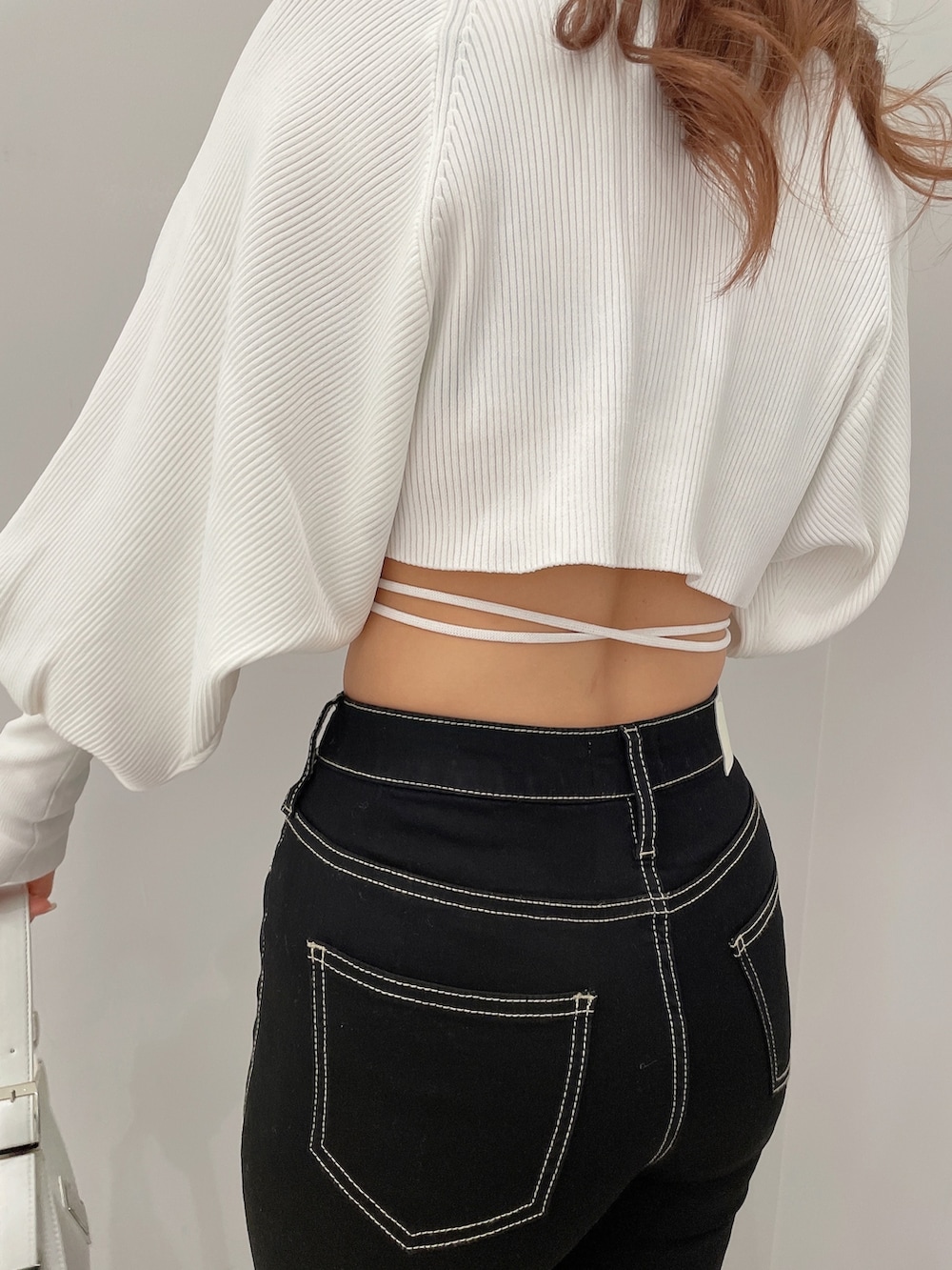 ブラック系のデニムパンツ、ブラック系のハンドバッグ、ホワイト系のパンプスを着用したレディースの春コーディネートの6枚目の写真