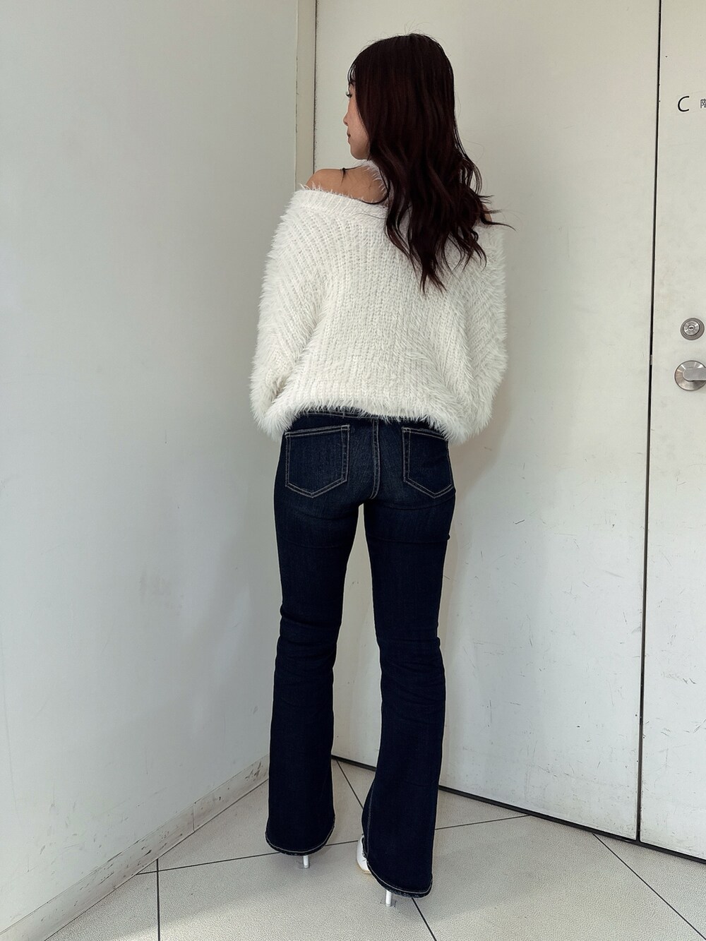 ホワイト系のニット/セーター、ブルー系のデニムパンツ、ホワイト系のパンプスを着用したレディースの秋コーディネートの3枚目の写真