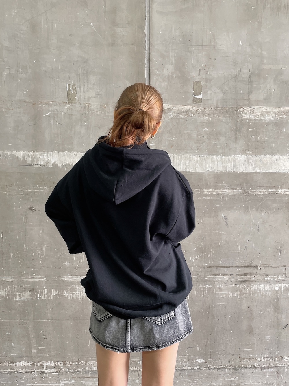 ブラック系のスウェット、ブラック系のデニムスカート、ブラウン系のブーツを着用したレディースの秋コーディネートの3枚目の写真