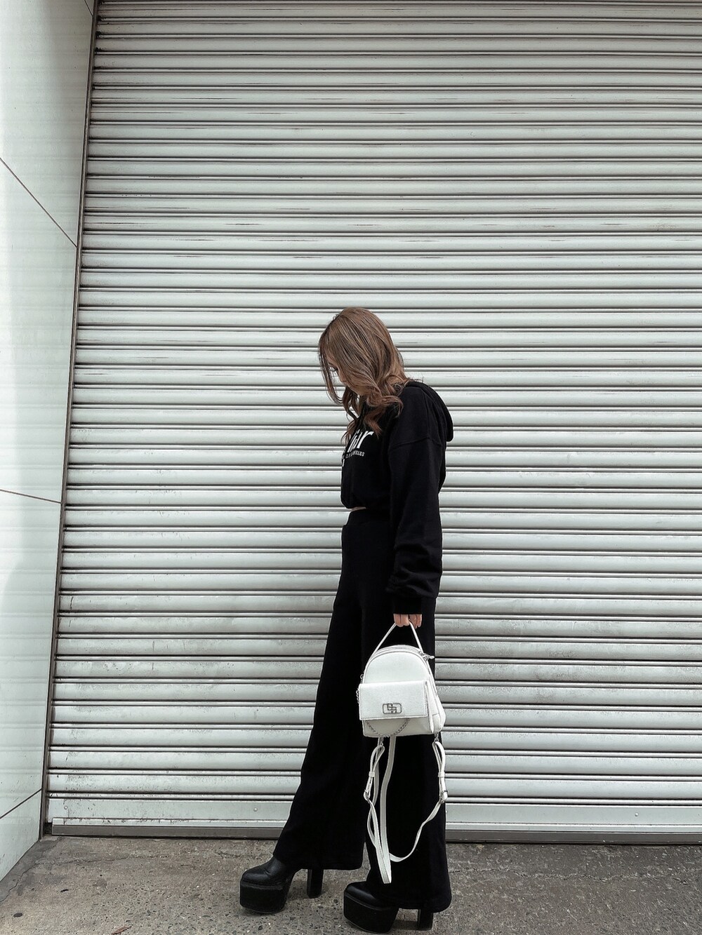 ブラック系のパーカー、ブラック系のスウェットパンツ、ホワイト系のバックパック/リュックを着用したレディースの冬コーディネートの2枚目の写真