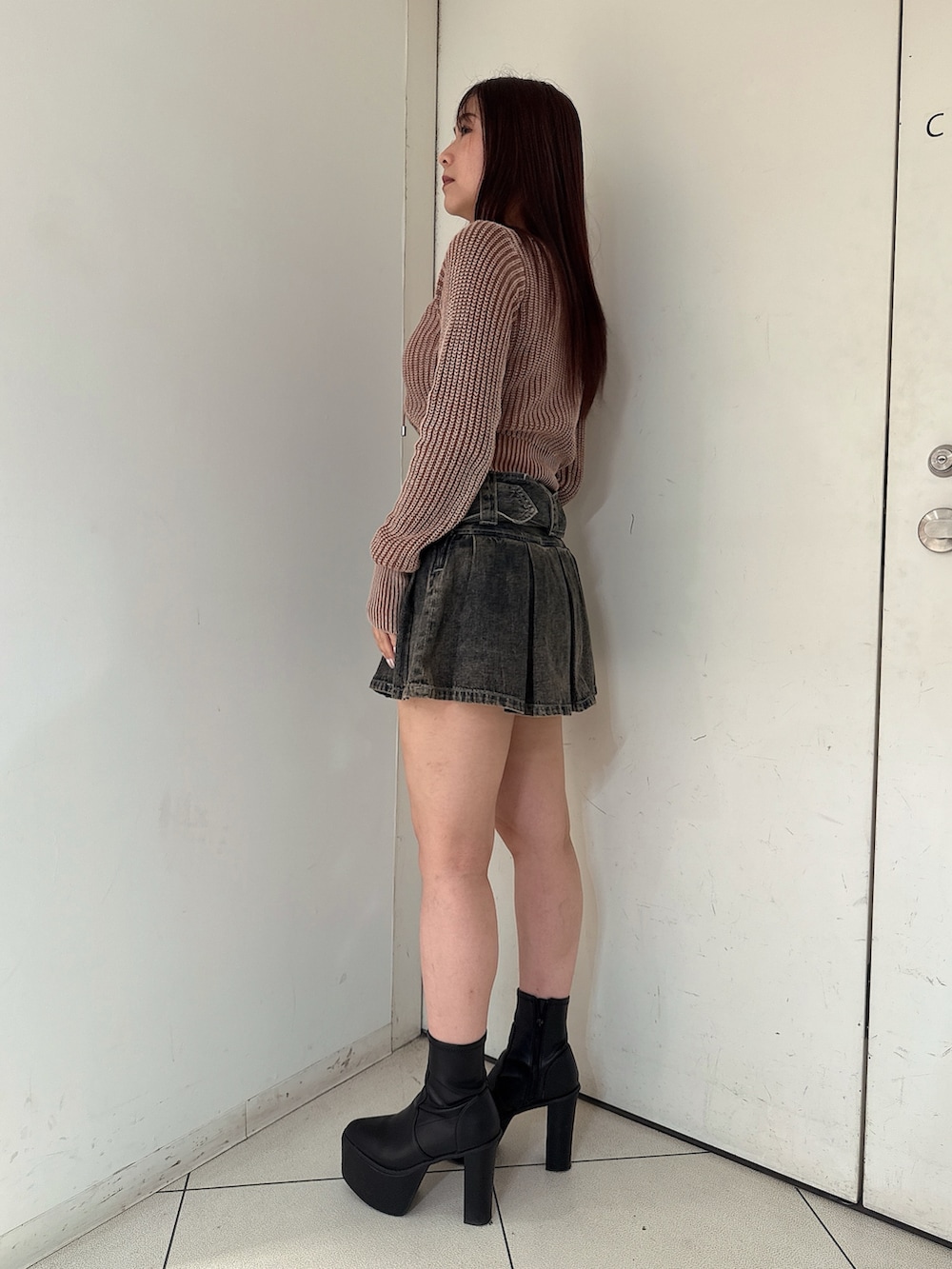 ブラウン系のニット/セーター、その他のデニムスカート、ブラック系のブーツを着用したレディースの秋コーディネートの2枚目の写真