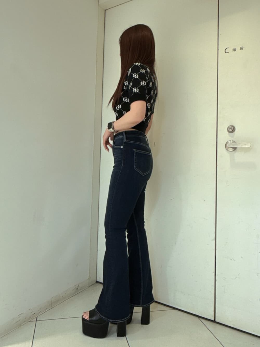 ブルー系のデニムパンツ、ブラック系のニット/セーター、ブラック系のサンダルを着用したレディースの春コーディネートの2枚目の写真