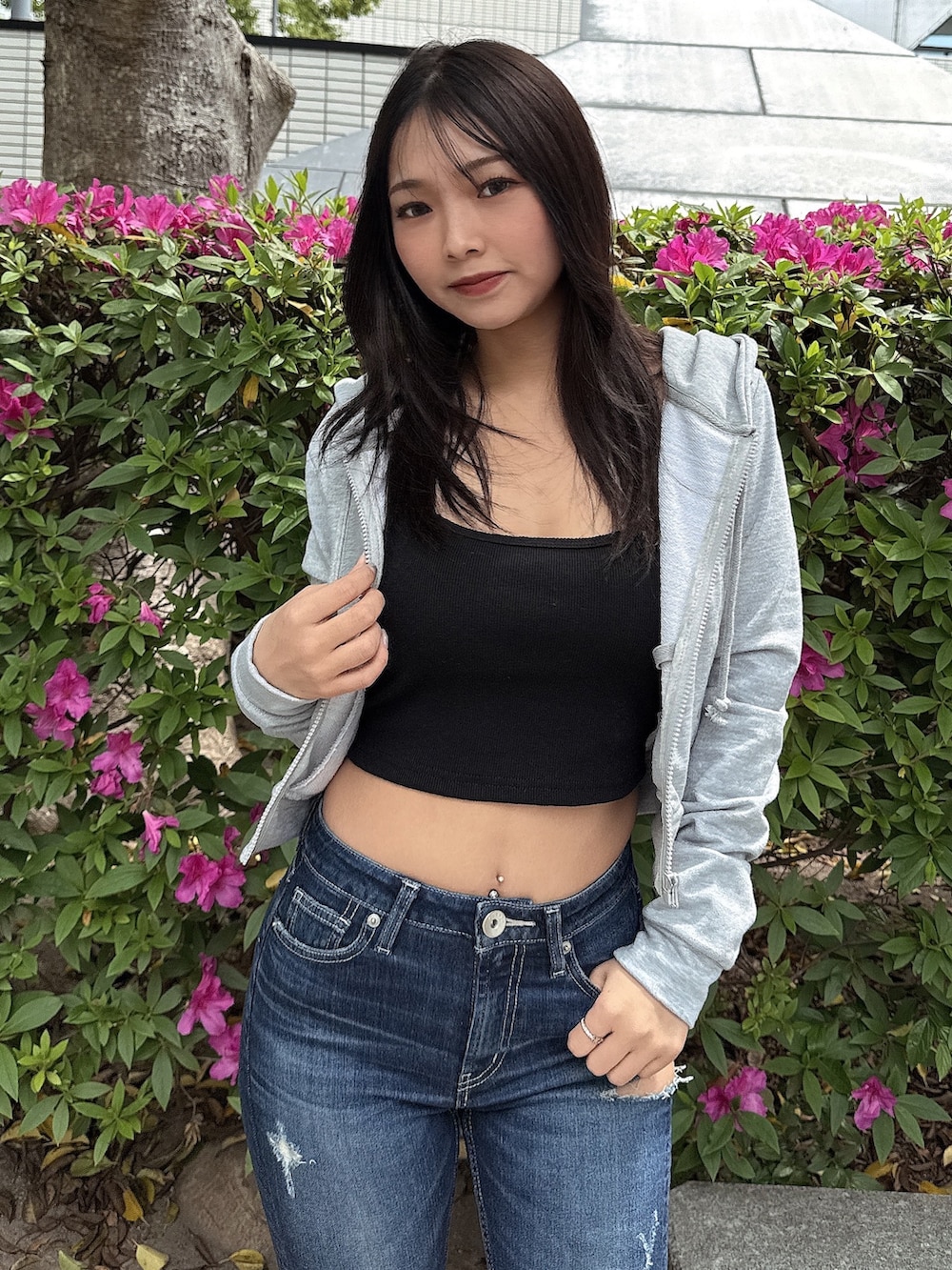 グレー系のパーカー、ブルー系のデニムパンツ、ホワイト系のサンダルを着用したレディースの春コーディネートの4枚目の写真